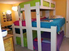 the bunk bed is made up with colorful bedspreads and pillows on it's sides