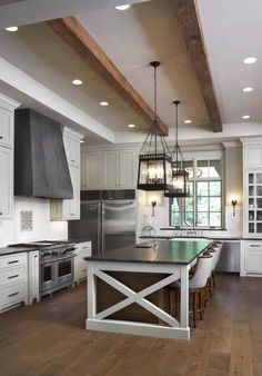 a kitchen with white cabinets and an island in the middle, surrounded by wood flooring