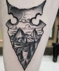 a black and white photo of a triangle with mountains in the background tattoo on the leg