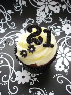 a cupcake with white frosting and black icing that has the number twenty on it