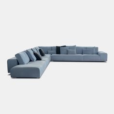 a blue sectional sofa with pillows on the top and bottom corner, in front of a white background