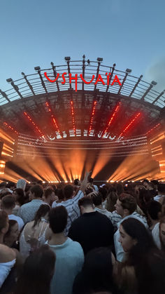 a large group of people standing in front of a stage with red lights on it