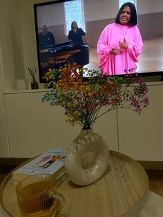 a vase filled with flowers sitting on top of a table in front of a tv