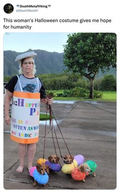 the woman is holding two dogs on leashes and wearing a sign that says happy halloween