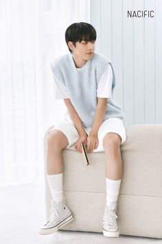 a young boy sitting on top of a couch wearing white socks and a blue sweater