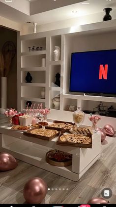 a table topped with lots of food next to a flat screen tv in a living room