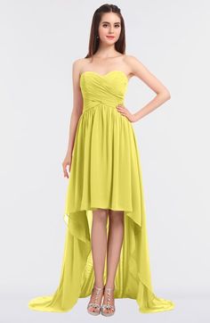 a woman in a strapless yellow dress with high low heels and her hands on her hips