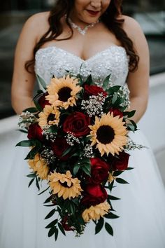 a bride holding a bouquet of sunflowers and roses