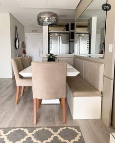 a dining room table and some chairs with a rug on the floor in front of it