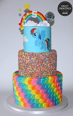 a three tiered cake decorated with an image of a rainbow horse on it's side