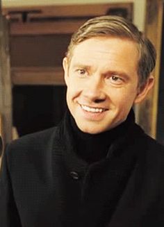 a man wearing a black coat and smiling at the camera