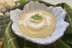 a white bowl filled with soup next to cauliflower