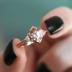 a woman's hand holding an engagement ring with two diamonds on top of it