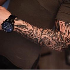 a man with a tattoo on his arm holding a wrist watch in his other hand