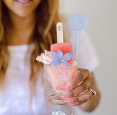 a woman holding a glass filled with ice cream and marshmallows