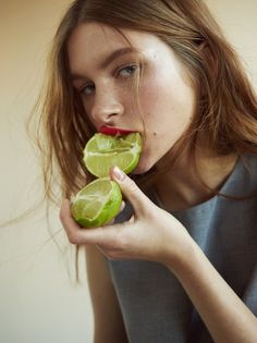 a woman is holding two limes in her hands and biting them into the other