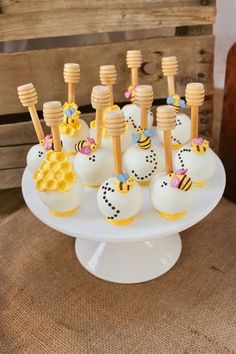 there are many cake pops with honey on them sitting on a white plate in front of a wooden crate