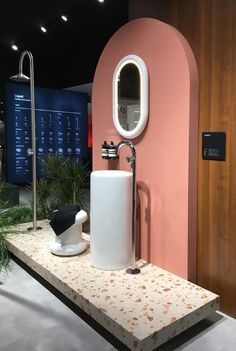 a bathroom with a sink, mirror and shower faucet on display in front of a pink wall