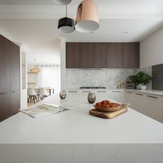 a kitchen with white counter tops and wooden cabinets in the corner, along with two hanging lights