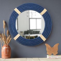 a blue rope is hanging on the wall next to a vase with flowers and a mirror