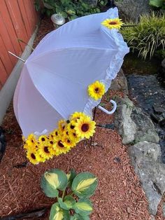 an umbrella with sunflowers attached to it sitting on the ground next to some rocks