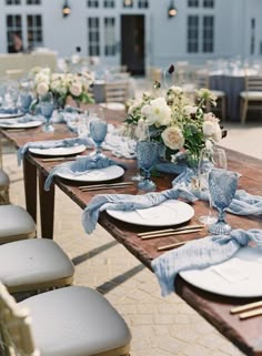 a long table set with blue and white plates, napkins and flowers on it