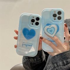 two cases with hearts painted on them are held up by someone's hand while they both have their fingers in the air