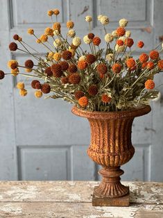 a vase filled with lots of flowers sitting on top of a wooden table next to a door