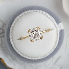 an engagement ring sitting on top of a white and gold plate with a diamond in the center