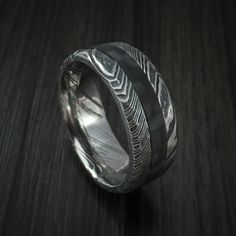 Kuro Damascus Steel and Carbon Fiber Ring Custom Made Hammered Band Black Etched Rings For Formal Occasions, Formal Black Etched Rings, Black Promise Ring With Polished Finish, Black Stainless Steel Jewelry With Engraving Option, Black Sterling Silver Jewelry With Engraving Option, Black Titanium Round Jewelry, Formal Black Engraved Ring With Engraving Option, Black Engraved Ring For Formal Occasions, Black Etched Sterling Silver Jewelry