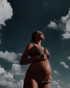 a pregnant woman standing on the beach with her belly up and head tilted to the side