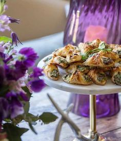 there is a platter full of food on the table next to purple vases