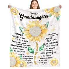 a woman holding up a white blanket with sunflowers and the words to my granddaughter