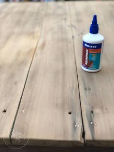 a bottle of glue sitting on top of a wooden table