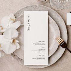 a plate with a menu on it next to a fork and glass vase filled with flowers