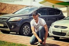 a man kneeling down next to a parked car