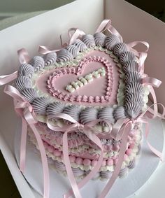 a heart shaped cake in a box with pink ribbon