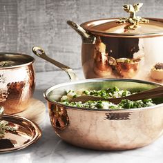 copper pots and pans are sitting on a table