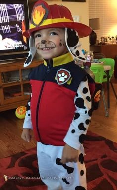 a little boy dressed up as a dalmatian in front of a tv wearing a fireman's hat