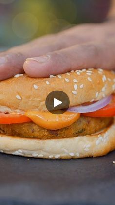 a hand holding a sandwich with meat, cheese and onions on it's bun