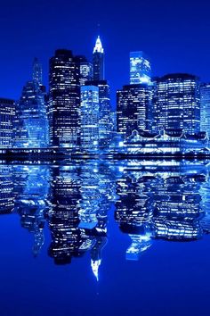 the city lights are reflecting in the water at night, and it looks like they're all lit up