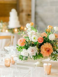 an arrangement of flowers and candles on a table at a wedding reception with white linens