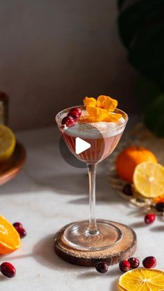 a glass filled with fruit and garnish on top of a white table next to sliced oranges