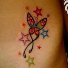 a colorful tattoo on the side of a woman's stomach with stars around it