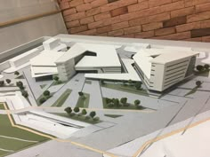 a model of a building with trees and buildings on the ground in front of it