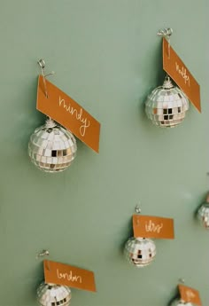 disco ball ornaments with name tags hanging from them on a green wall in an office