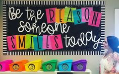 a woman standing in front of a sign that says be the reason someone smiles today