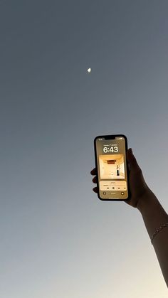 someone is holding up their cell phone to take a photo with the moon in the background