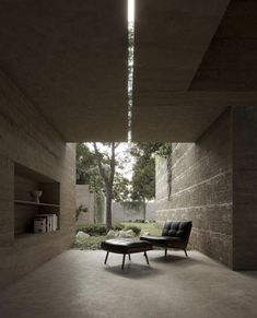 an empty living room with concrete walls and flooring, as well as a lounge chair