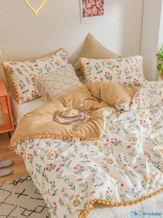 an unmade bed in a bedroom with flowers on the comforter and pillow cases